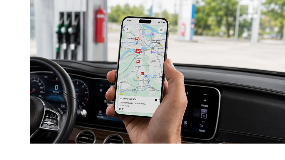 Ruka drži pametni telefon s prikazom karte i lokacija Petrolovih prodajnih mjesta, dok se u pozadini vidi unutrašnjost automobila i postaja za gorivo.