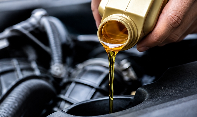 Na slici je sipanje motornog ulja u motor automobila tokom redovnog održavanja vozila.