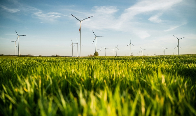 Na slici je vetropark sa više vetroturbina na zelenoj livadi kao prikaz proizvodnje energije iz obnovljivih izvora.